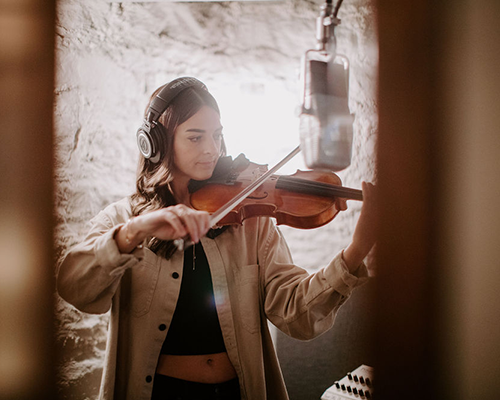 woman playing instrument into mic in Ivy Hall recording studio